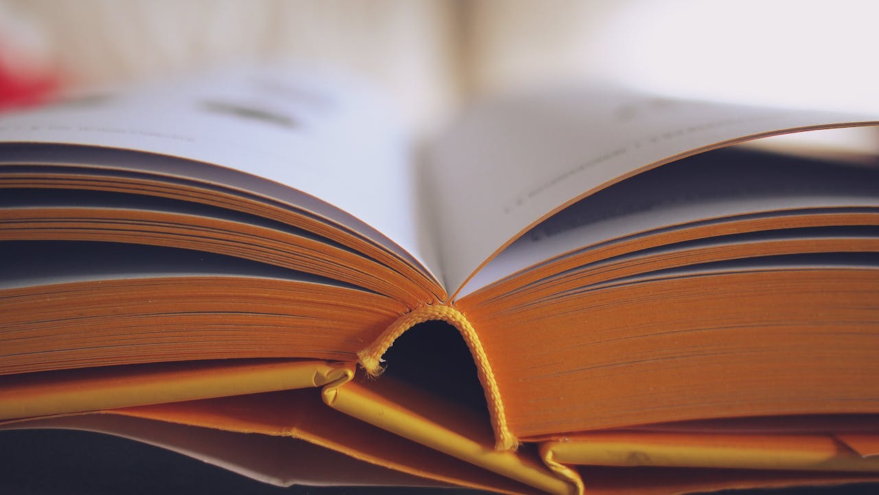 Close-up of an open book with a yellow spine, symbolising knowledge, learning, and essential books for students.